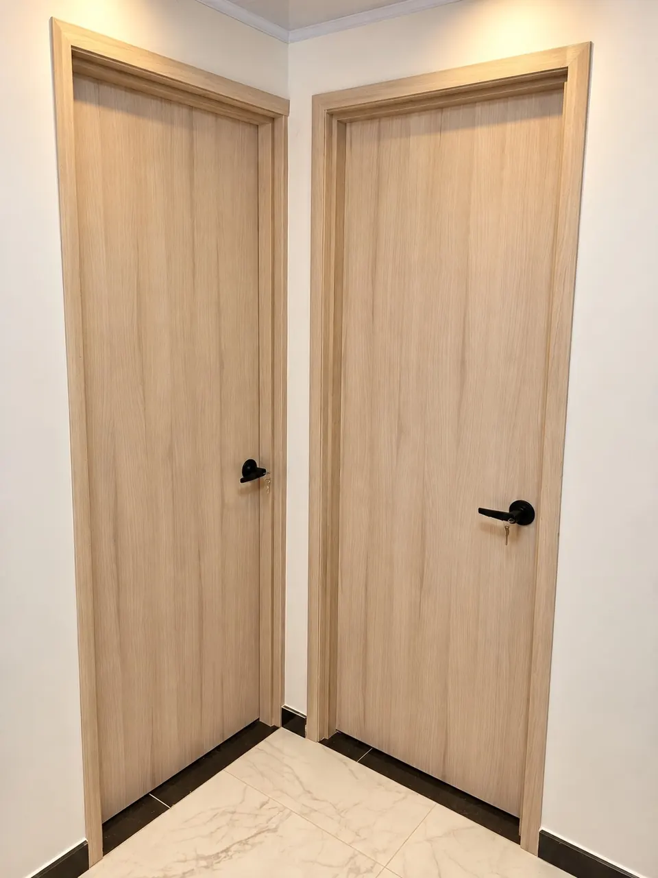 Dos puertas interiores en tono claro con manijas negras, en esquina