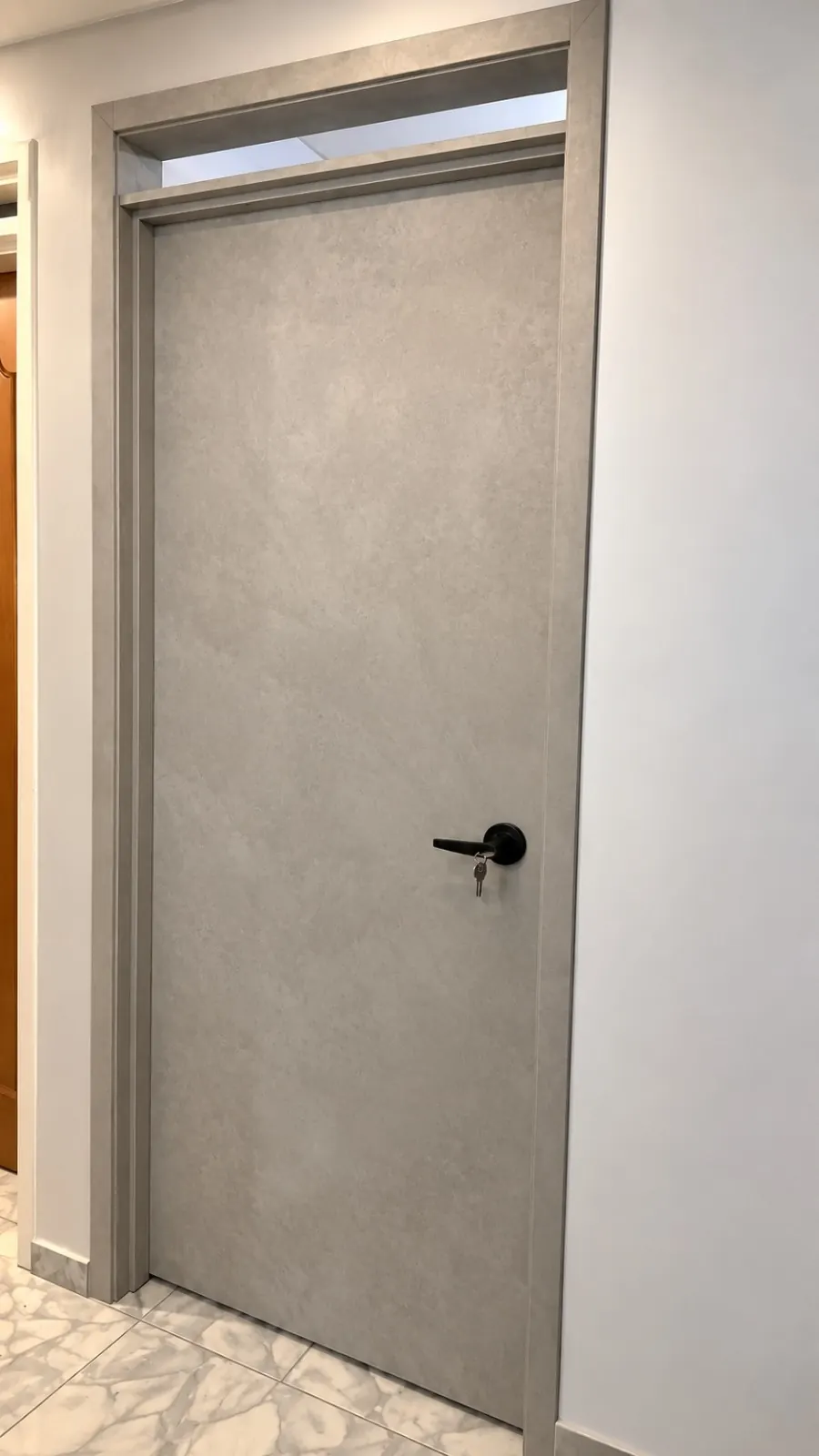 Puerta interior en gris tono cemento con manija negra y ventanilla arriba